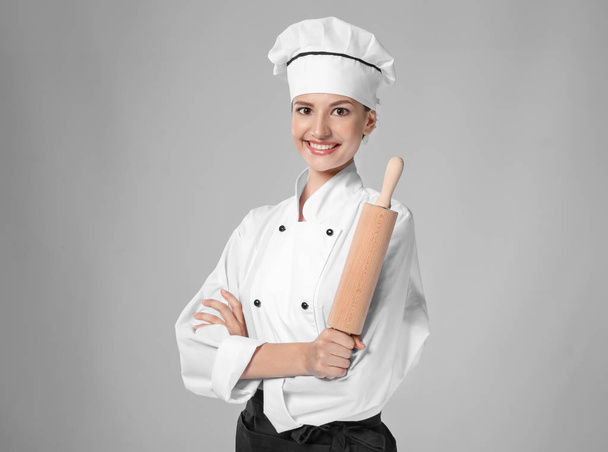 Young female chef with rolling pin on light background - Fotografie, Obrázek