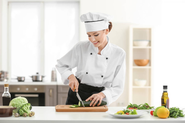 Young female chef cooking in kitchen - Foto, imagen