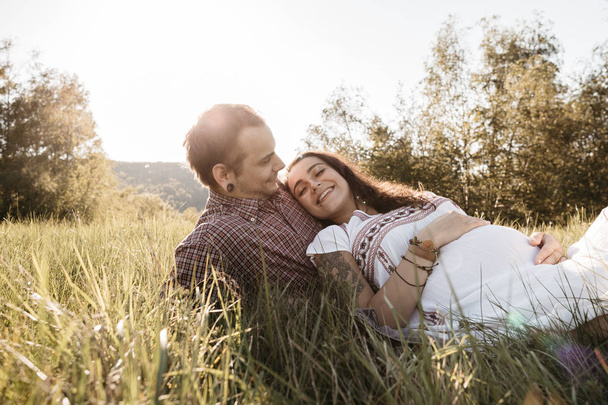 Szczęśliwa para w ciąży spoczywa na trawnik zabawie - Zdjęcie, obraz