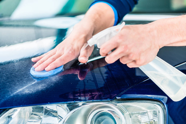 young man waxing blue car - 写真・画像