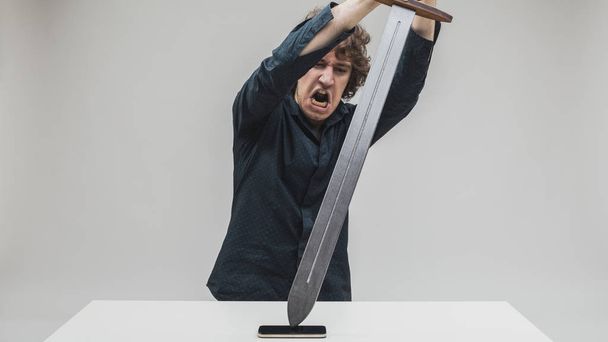 hombre enojado golpeando su teléfono con una espada
 - Foto, Imagen
