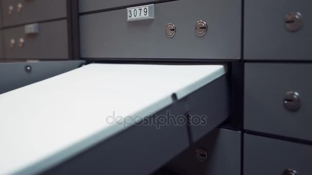 Руки старика помещают пластиковый ящик в ячейку банковского сейфа
 - Кадры, видео