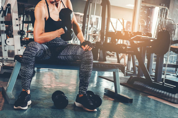 Mujer deportiva asiática haciendo ejercicios con pesas de mancuerna en el gimnasio
 - Foto, imagen