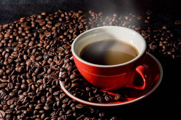 Sıcak kahve kırmızı Kupası ve kahve çekirdekleri arka plan vardır. - Fotoğraf, Görsel