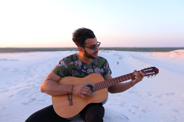 Милий молодий чоловік Арабські користується звук гітари, сидячи на пагорбі в - Фото, зображення
