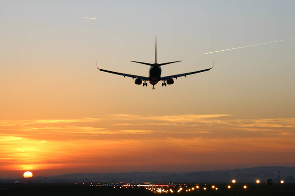 літак приземляється на аеродромі на тлі заходу сонця
 - Фото, зображення