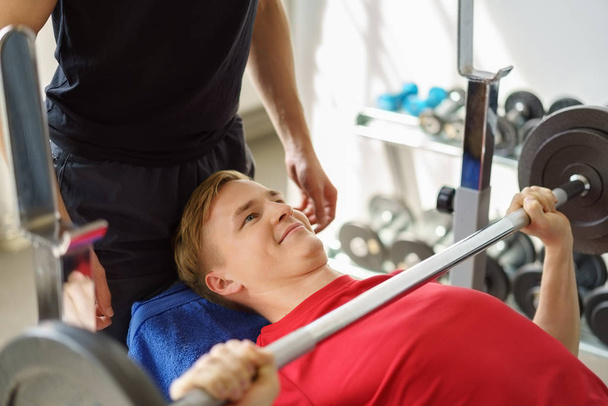 Young man doing barbell bench press at gym - Fotoğraf, Görsel