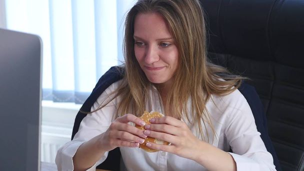 young business woman sitting in the office and eating a burger - Foto, Bild