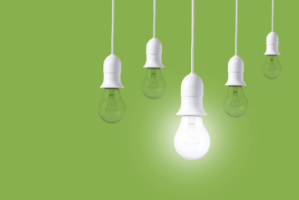 緑の背景違い電球。新しいアイデアの概念  - 写真・画像