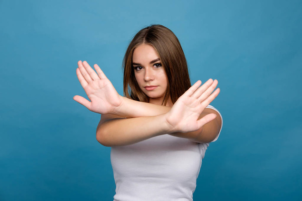 brunet meisje in weigeren expressie, blauwe achtergrond - Foto, afbeelding