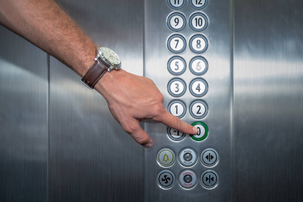 Forefinger pressing the zero floor button in the elevator - Photo, Image