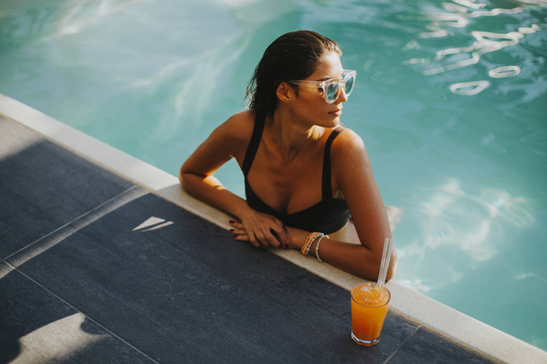 Young woman by the swimming pool with coctail - Foto, imagen