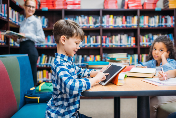 schoolboy using tablet at library - Photo, Image