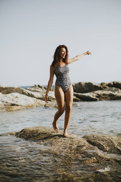 Красивая молодая женщина на каменистом берегу
 - Фото, изображение