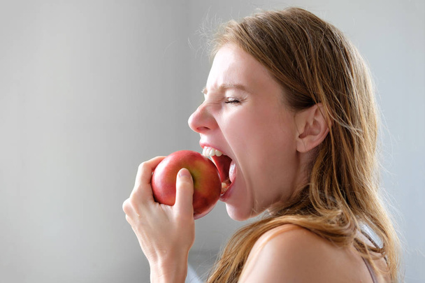 young redhead skinny woman biting red apple, healthy lifestyle c - Photo, Image