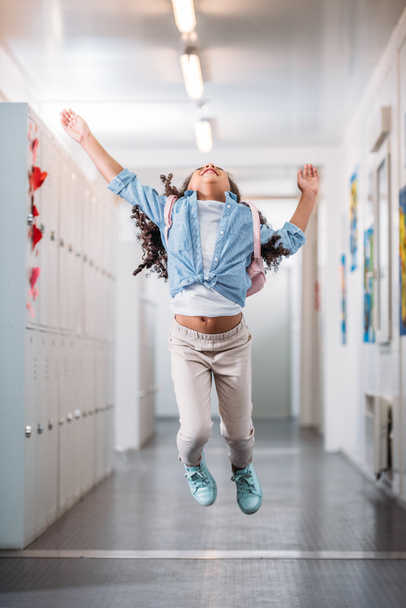 girl jumping in school corridor - Foto, afbeelding