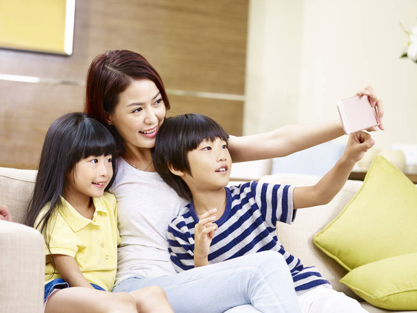 Aziatische moeder en kinderen die thuis een selfie nemen - Foto, afbeelding