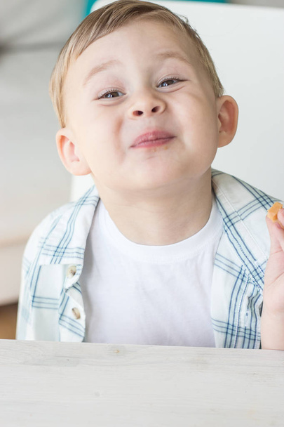 かわいい男の子はキャンディを食べる、牛乳を飲みます。健康。幸せな子。朝食。小さな男の子はテーブルに座っています。. - 写真・画像