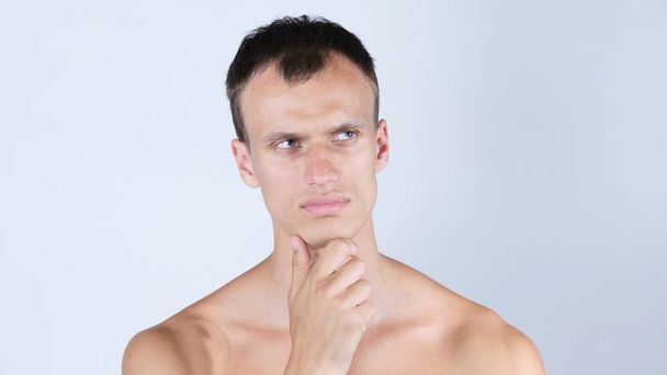 Portrait of shirtless man keeping his hands by face while thinking - Photo, Image