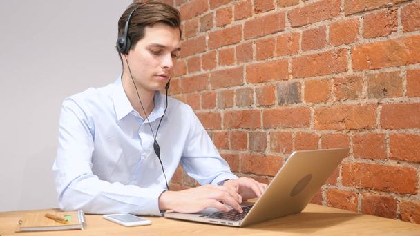 Hombre usando auriculares para hablar, trabajando en línea
 - Foto, imagen