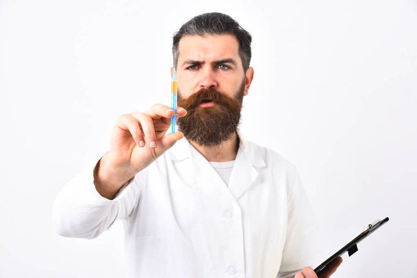 Bearded doctor with stylish haircut holds syringe and black folder - Fotó, kép