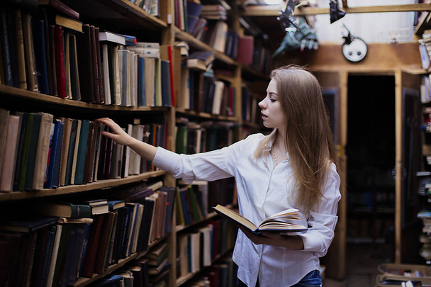 Lifestyle portrait of a lovely student girl in vintage library or bookstore - Foto, imagen
