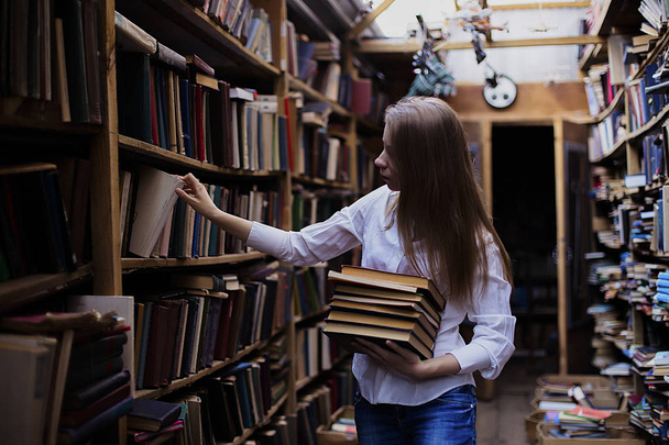Lifestyle portrait of a lovely student girl in vintage library or bookstore - Foto, Imagen