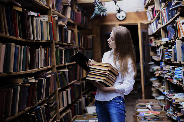 Lifestyle portrait of a lovely student girl in vintage library or bookstore - Φωτογραφία, εικόνα