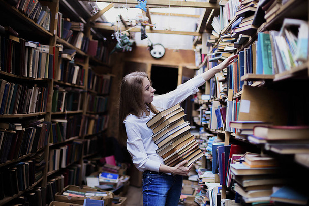 Lifestyle portrait of a lovely student girl in vintage library or bookstore - Zdjęcie, obraz