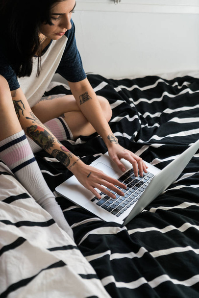 Feminino digitando no laptop sentado na cama
 - Foto, Imagem