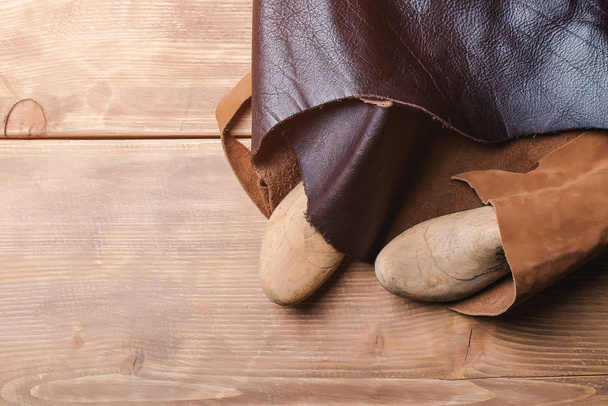 Dura de madeira para um sapato de crianças e pedaço de couro em uma oficina. Espaço para texto
. - Foto, Imagem