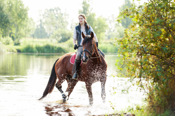 Young teenage girl riding horseback in river at early morning - Photo, Image