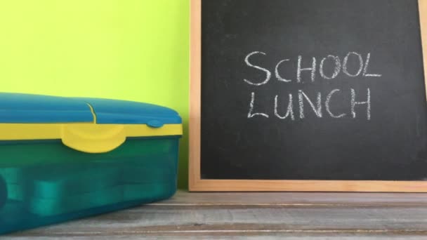 Σημάδι μεσημεριανό σχολείο σε έναν πίνακα με καλαθάκι με φαγητό  - Πλάνα, βίντεο