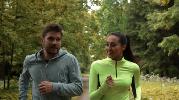 Girl and guy communicating and smiling during morning jog. They running at the park. - Footage, Video