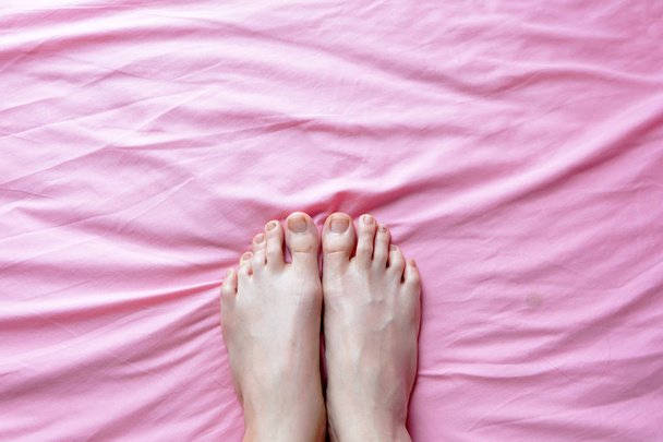 Close Up of Female Feet and Slim Legs on the Pink Bed, Feet in the Bedroom Background at Home - Valokuva, kuva