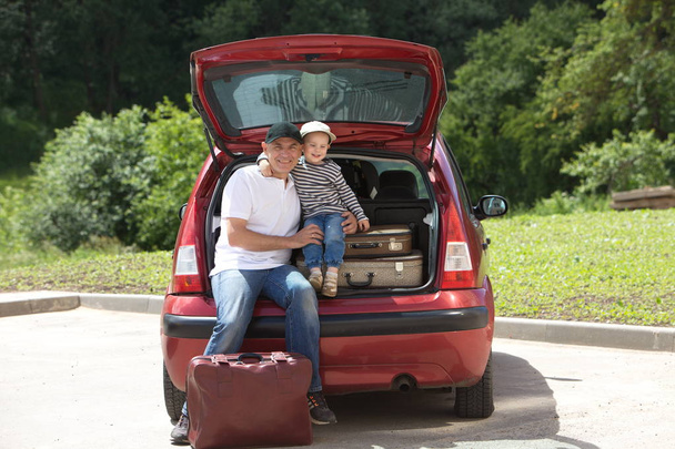 A man and kid loads his car  suitcases - Fotó, kép