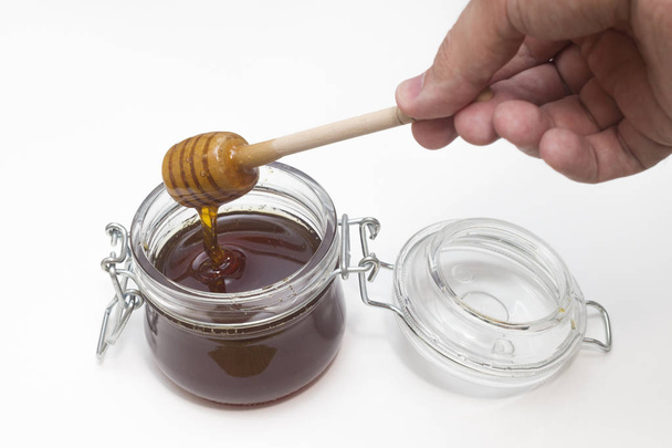 лиття меду в скляному горщику на білому
 - Фото, зображення