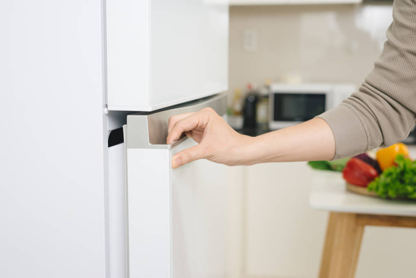 La mano maschile sta aprendo la porta del frigorifero bianco
 - Foto, immagini