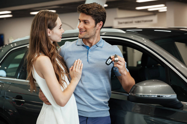 Woman standing near car with boyfriend in car dealership - Foto, afbeelding