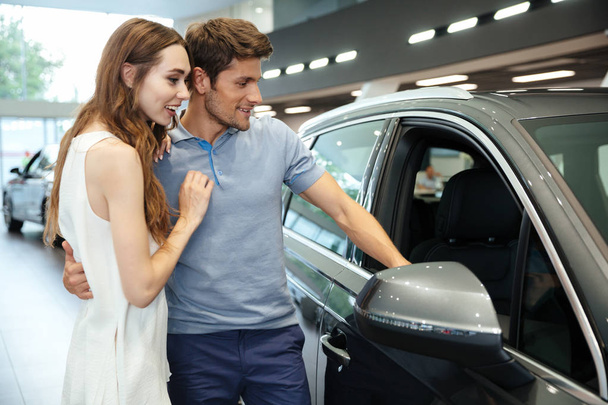 Smiling young couple choosing a car at the dealership - Foto, Imagem