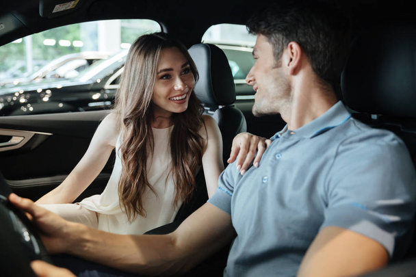 Young couple sitting inside new car - Фото, изображение