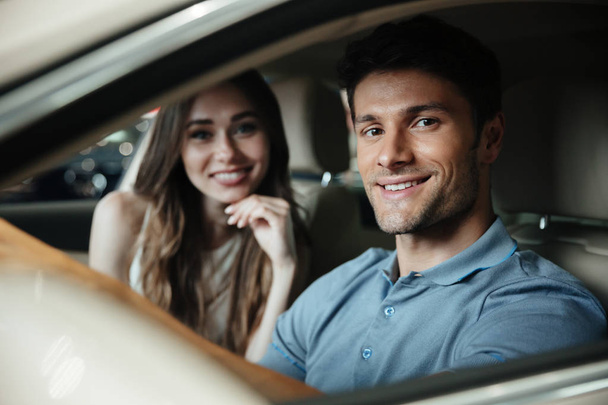 Smiling young couple sitting at the front seat of the car - Photo, image