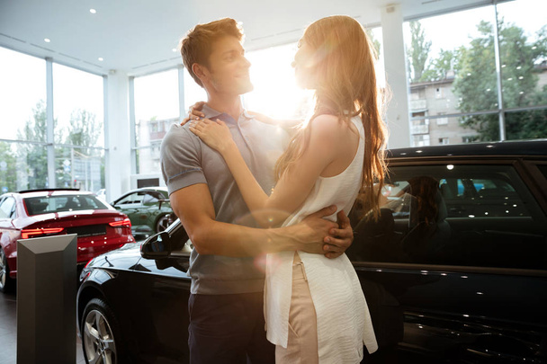 Happy young couple hugging after buying a new car - Foto, Imagen