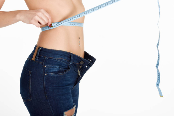 Young woman measuring waist with a tape - Fotó, kép