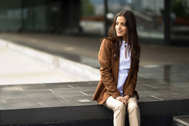 Молода бізнес-леді, що сидить за межами офісної будівлі в місті
  - Фото, зображення