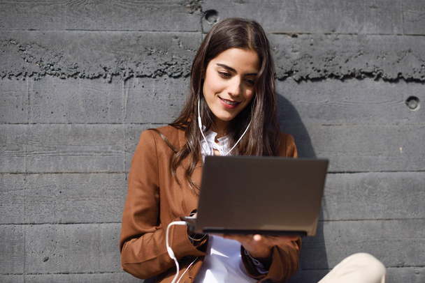 Молода бізнес-леді сидить на підлозі, дивлячись на її ноутбук
 - Фото, зображення