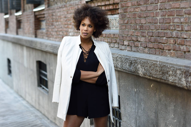 Młody czarny kobieta z fryzura afro stojący w miejskich backgrou - Zdjęcie, obraz
