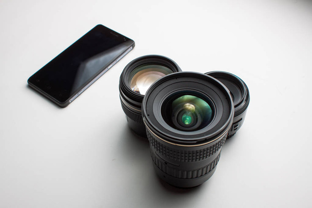 close-up de grupo de lentes de câmera e um telefone celular em um branco
 - Foto, Imagem
