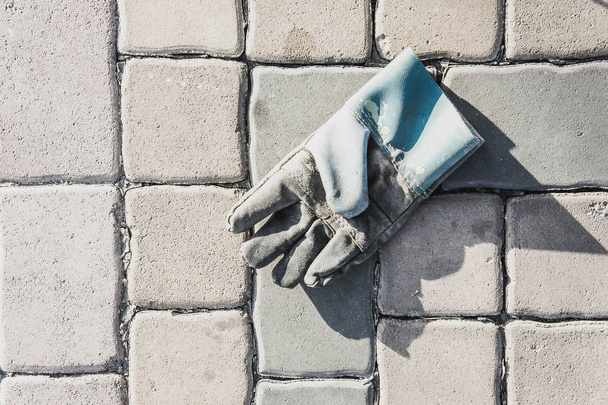 Old leather gloves leave on paving footpath background  - Photo, Image