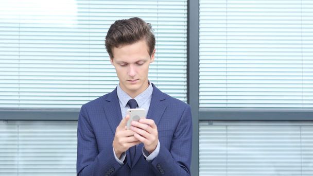 Молодий підприємець за допомогою смартфона, за межами офісу - Фото, зображення